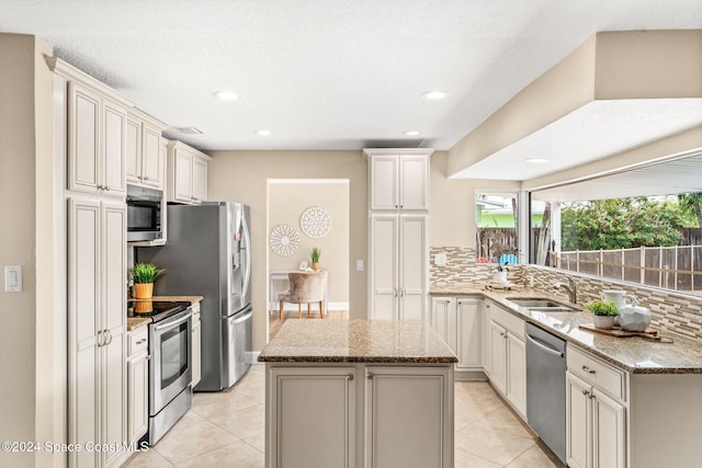 kitchen with a kitchen island, light stone countertops, stainless steel appliances, and tasteful backsplash