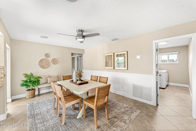 dining space featuring ceiling fan, light tile patterned flooring, a textured ceiling, and washing machine and clothes dryer