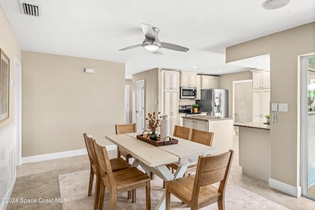 tiled dining room featuring ceiling fan and a textured ceiling