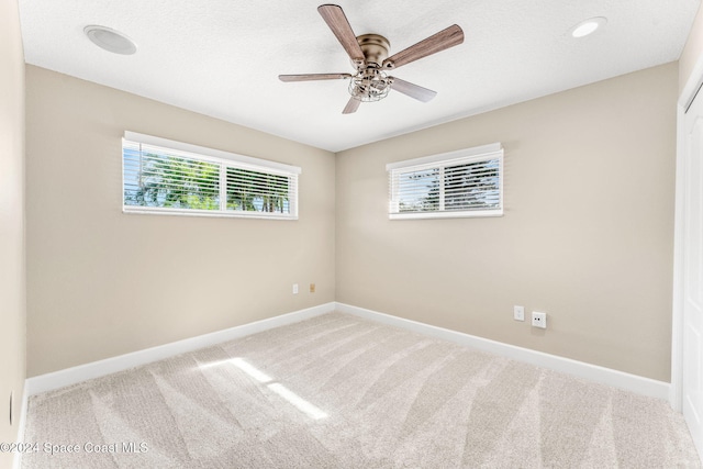 unfurnished room with carpet flooring, ceiling fan, and a wealth of natural light