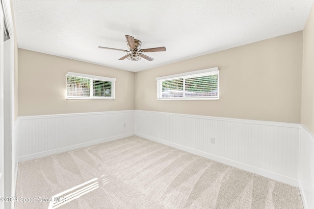 carpeted spare room with ceiling fan and a textured ceiling