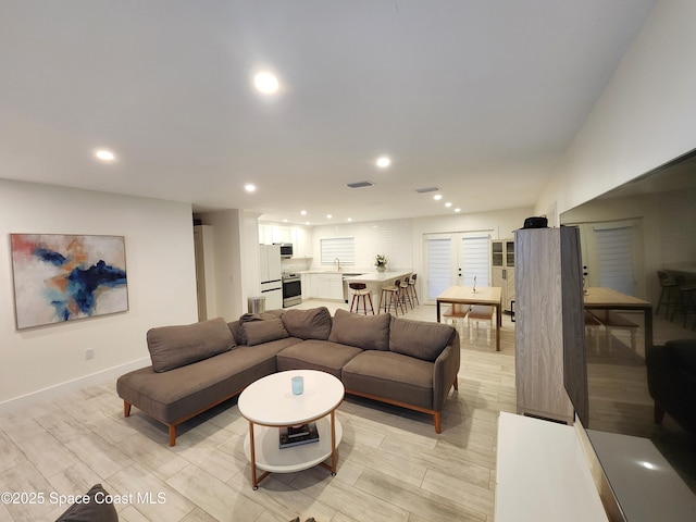 living area with baseboards, wood tiled floor, visible vents, and recessed lighting