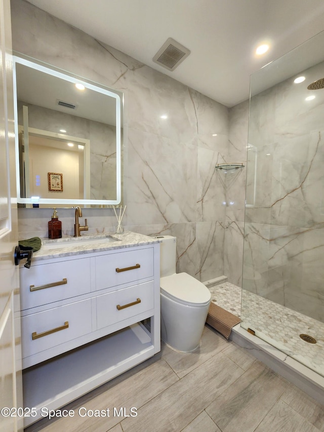 bathroom featuring toilet, vanity, a marble finish shower, and visible vents