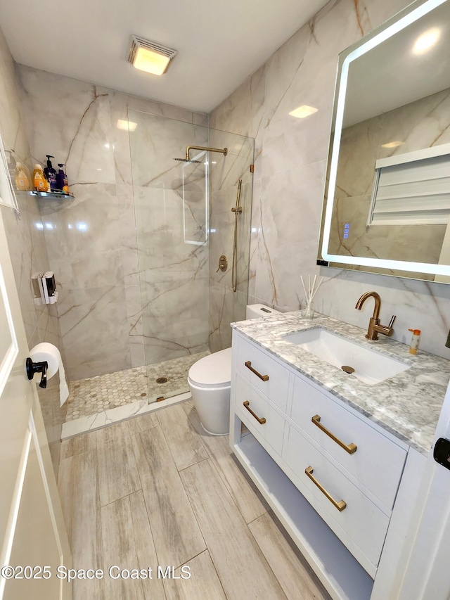 full bathroom featuring toilet, a marble finish shower, and vanity