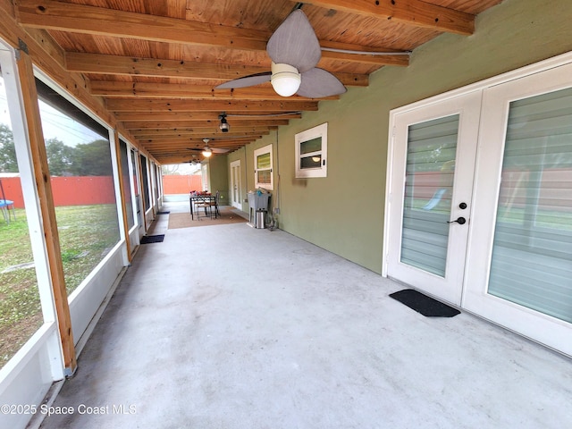 unfurnished sunroom featuring wood ceiling, french doors, beamed ceiling, and ceiling fan