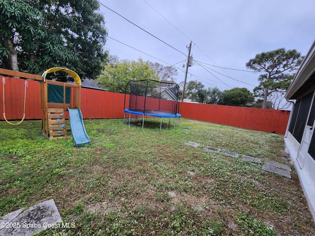 view of yard with a trampoline, a playground, and a fenced backyard