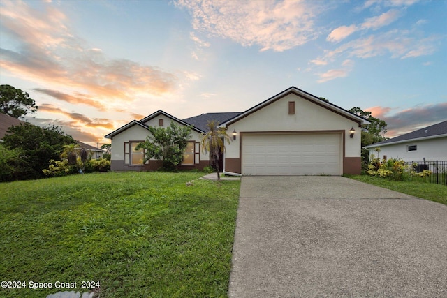 single story home featuring a garage and a yard