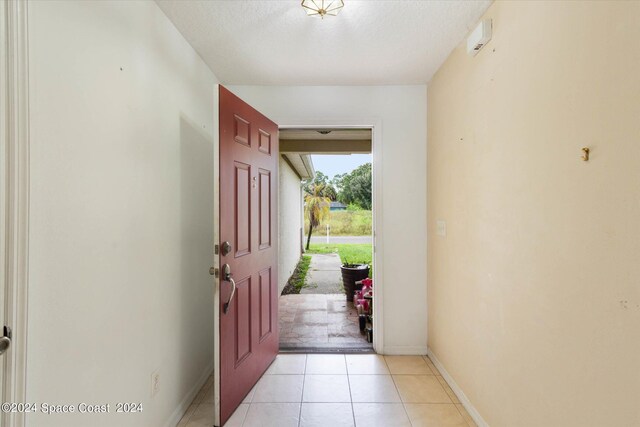 foyer with a textured ceiling and light tile patterned floors