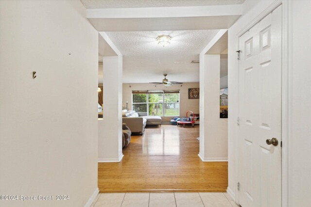 hall featuring a textured ceiling and light hardwood / wood-style flooring