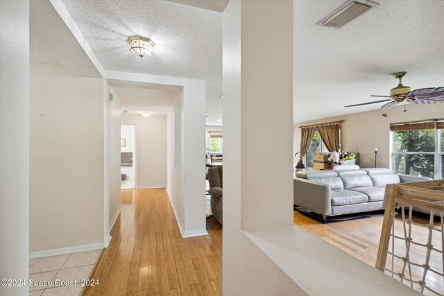 hallway featuring light wood-type flooring and a textured ceiling