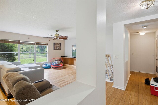 living room featuring a textured ceiling, light hardwood / wood-style flooring, and ceiling fan