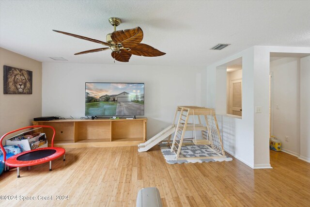 recreation room with a textured ceiling, ceiling fan, and hardwood / wood-style floors