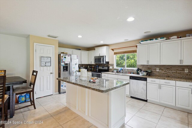 kitchen with a kitchen island, stainless steel appliances, decorative backsplash, and white cabinetry