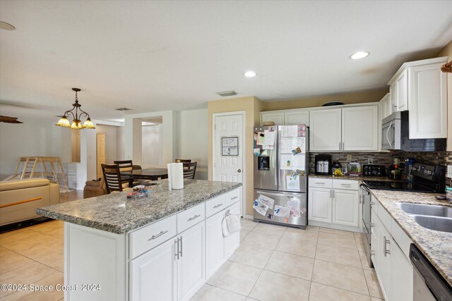 kitchen featuring white cabinets, appliances with stainless steel finishes, a kitchen island, and a notable chandelier