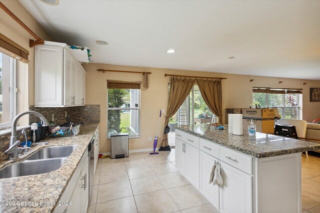 kitchen featuring white cabinets, sink, decorative backsplash, stone counters, and light tile patterned flooring