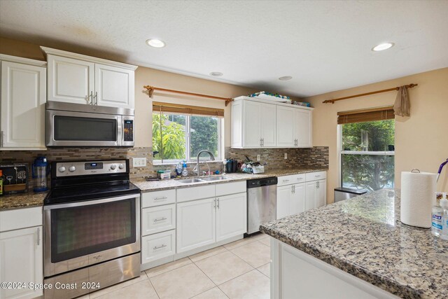 kitchen featuring stainless steel appliances, sink, light stone countertops, and white cabinets