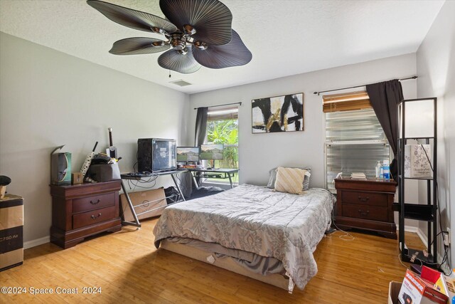 bedroom featuring light wood-type flooring, ceiling fan, and a textured ceiling