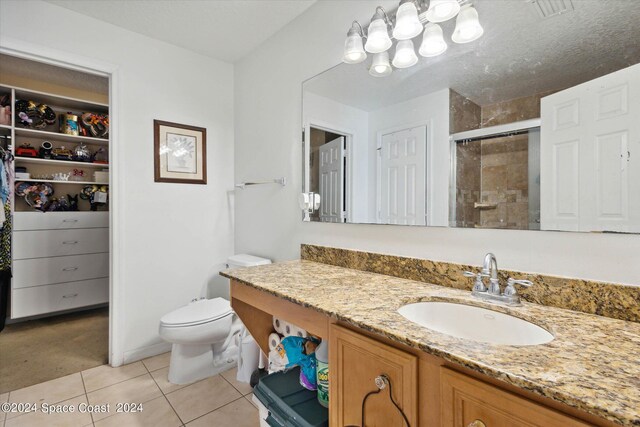 bathroom featuring a shower with door, vanity, toilet, and tile patterned floors