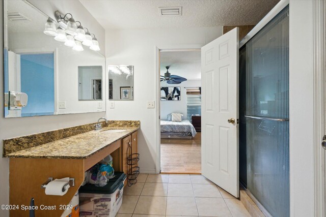 bathroom featuring a shower with door, vanity, a textured ceiling, tile patterned floors, and ceiling fan