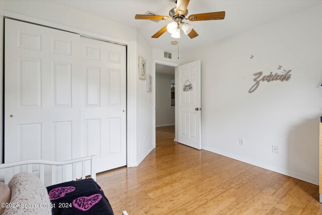 bedroom featuring ceiling fan, a closet, and light wood-type flooring