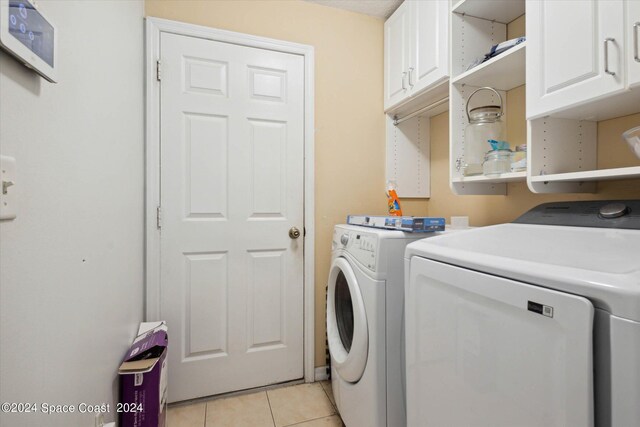 laundry room with cabinets, independent washer and dryer, and light tile patterned flooring