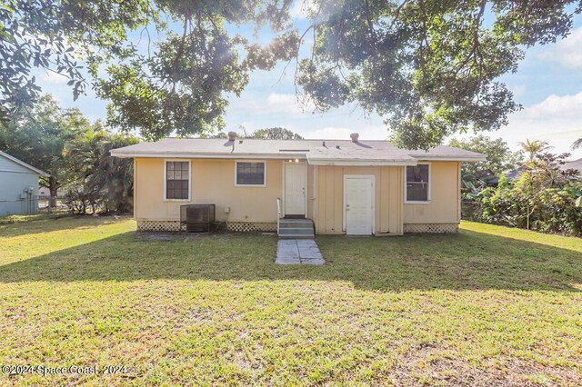 rear view of property with a lawn and central air condition unit