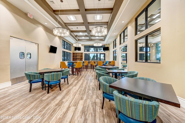 dining area with beam ceiling, a chandelier, light hardwood / wood-style flooring, a towering ceiling, and coffered ceiling