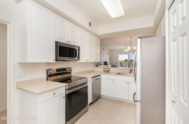 kitchen with light tile patterned flooring, white cabinets, stainless steel appliances, and hanging light fixtures