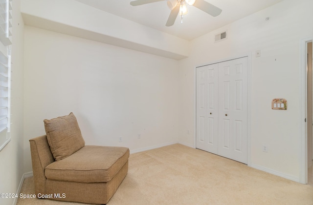 living area featuring light carpet and ceiling fan