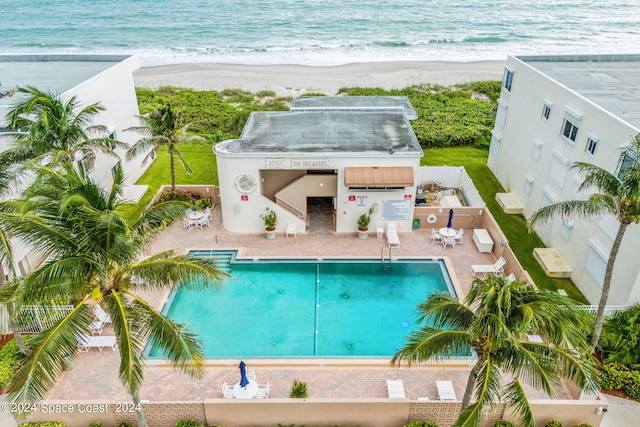 view of pool featuring a water view, a view of the beach, and a patio area