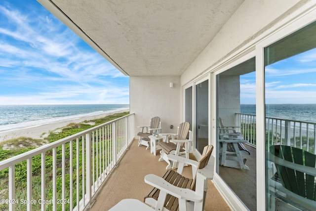 balcony featuring a view of the beach and a water view