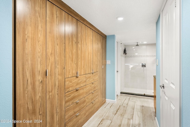 hall with a textured ceiling and light hardwood / wood-style floors