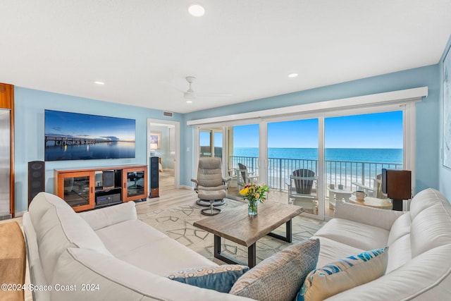 living room with ceiling fan, light wood-type flooring, and a water view