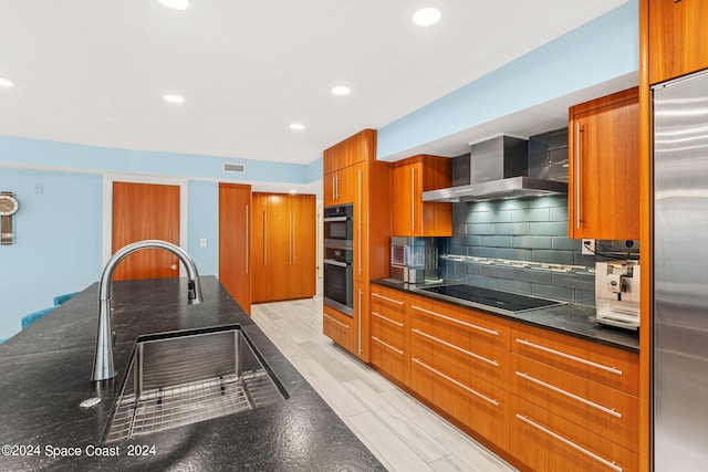 kitchen featuring light wood-type flooring, sink, wall chimney range hood, black appliances, and tasteful backsplash