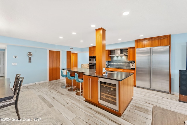 kitchen featuring light hardwood / wood-style floors, built in refrigerator, beverage cooler, a kitchen bar, and a kitchen island