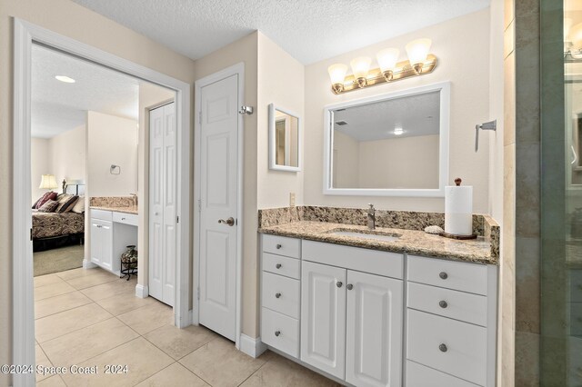 bathroom with tile patterned flooring, vanity, and a textured ceiling