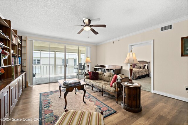 living room with a textured ceiling, ceiling fan, ornamental molding, and hardwood / wood-style flooring