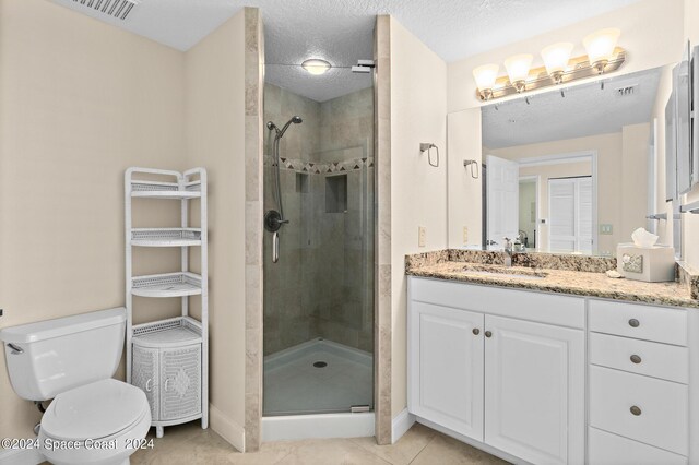 bathroom featuring vanity, toilet, a shower with shower door, and tile patterned floors