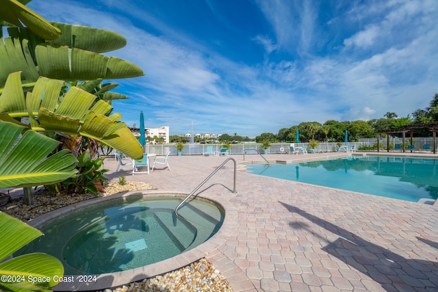 view of swimming pool with a water view, a community hot tub, and a patio