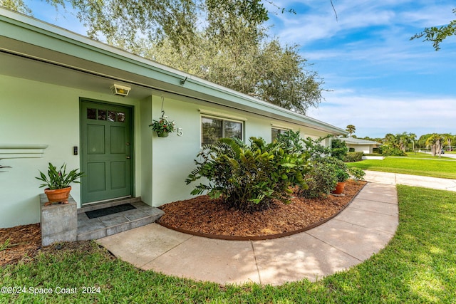 view of exterior entry featuring a lawn