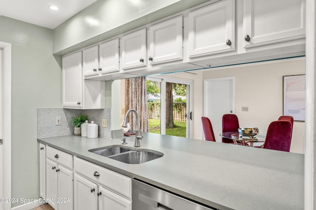 kitchen featuring tasteful backsplash, dishwasher, white cabinetry, and sink