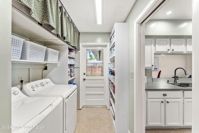 clothes washing area featuring cabinets, washing machine and clothes dryer, and sink