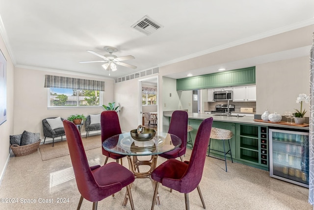 dining space with ornamental molding, ceiling fan, wine cooler, and sink