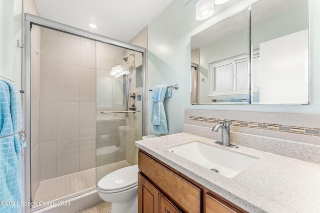 bathroom featuring toilet, a shower with door, decorative backsplash, and vanity