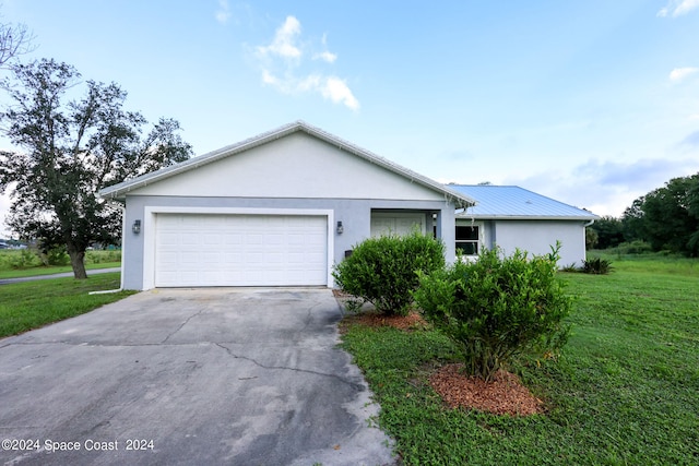 ranch-style house featuring a front yard, an attached garage, concrete driveway, and stucco siding