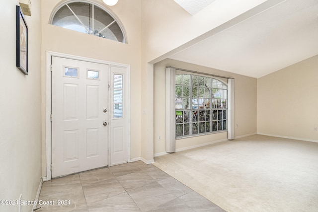 foyer entrance with light carpet and a towering ceiling