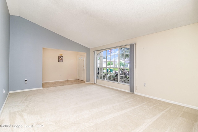 carpeted empty room with vaulted ceiling and a textured ceiling