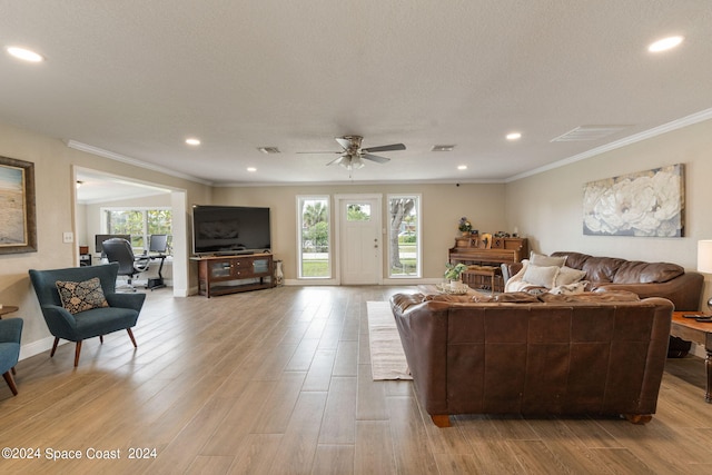 living room featuring light wood-type flooring, ornamental molding, plenty of natural light, and ceiling fan