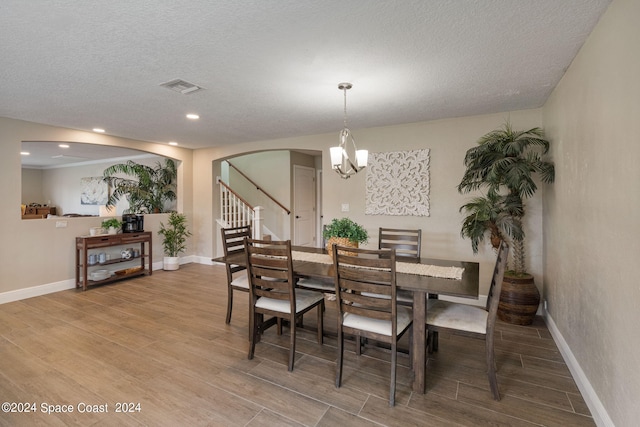 dining area with a textured ceiling, hardwood / wood-style flooring, and a chandelier