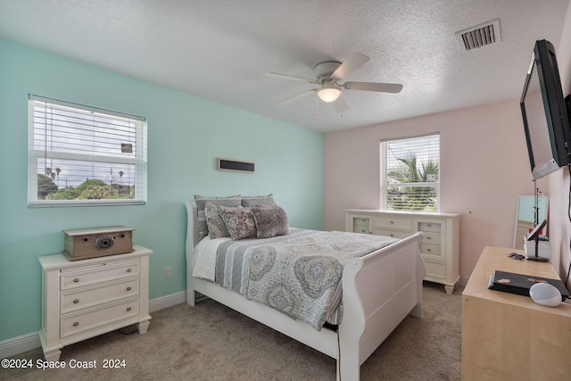 bedroom with a textured ceiling, light colored carpet, and ceiling fan